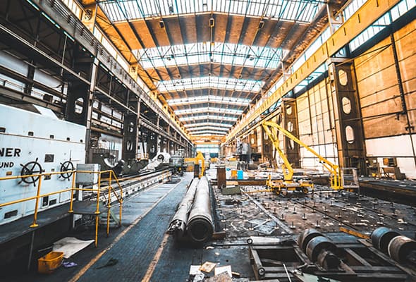 Industrial workshop scene with heavy machinery and scattered equipment, indicative of robust manufacturing processes.